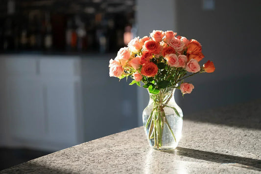 A peach rose flower arrangement in a vase displayed on a sunlit kitchen counter, offering an effortless way to decorate the home