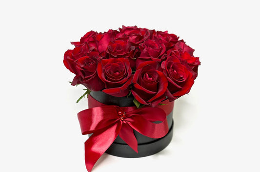 Elegant red roses arranged in a black gift box with a satin ribbon, creating a romantic wedding anniversary bouquet.