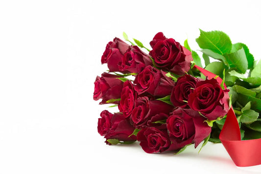 Twelve long-stemmed red roses resting on a table surface, the classic dozen rose bouquet associated with romantic love and a timeless gesture